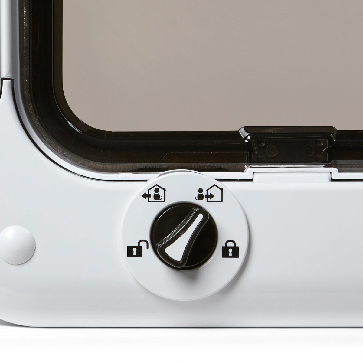 Close-up of a rotary control dial with four settings for a pet door. The dial is black with a white background and is currently pointing to a mode symbolized by a cat entering a house. Clockwise from top left: a symbol of a cat exiting a house, a cat entering a house, a locked padlock icon, and an unlocked padlock icon