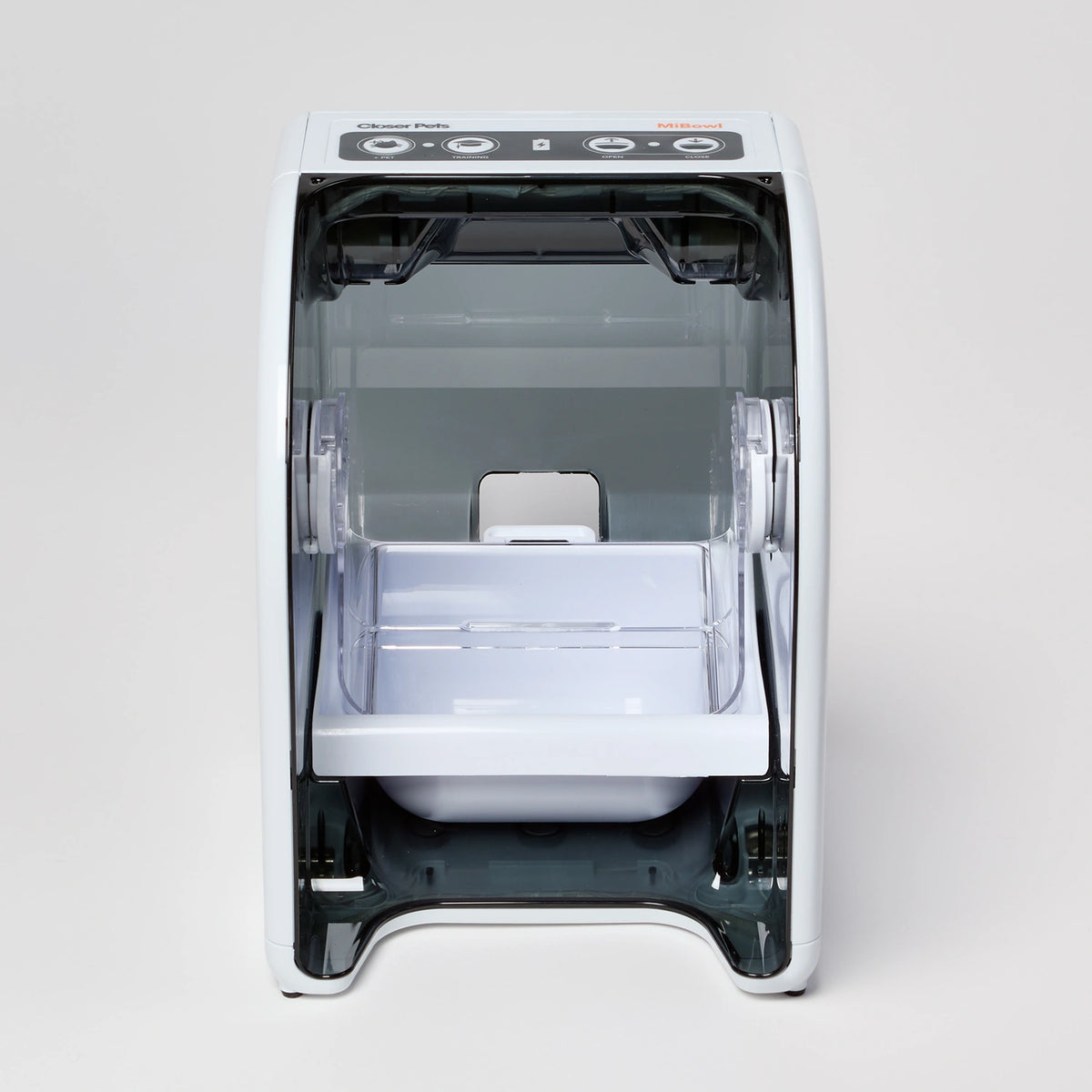 A white plastic food tray inside a white and black plastic enclosed feeding stand with visible brand logo on a white background